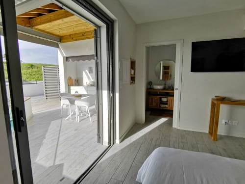 Chambre moderne à l'Habitation l'SEO à Sainte-Anne avec vue océan par les portes vitrées donnant sur la terrasse et la salle de bain.