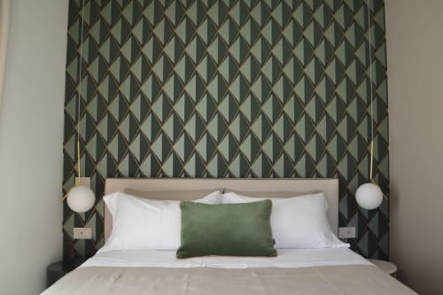 Camera Muschio di Villa Rosati con testata a motivi geometrici, biancheria bianca, cuscino verde e applique moderne