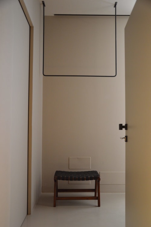 Nicchia minimalista in camera da letto a Villa Rosati con panchina in legno, doccia a pioggia e pareti neutre a Sanzeno, Italia