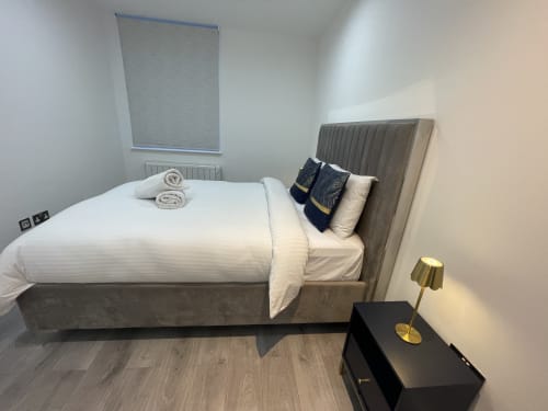 Modern one-bedroom suite at Empire Serviced Apartments Leicester with made bed, neutral decor, and contemporary furnishings