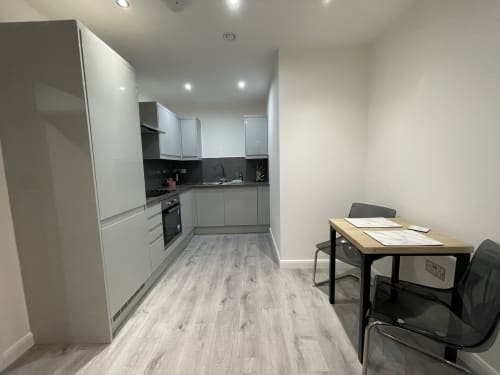 Modern one-bedroom apartment at Empire Serviced Apartments Leicester with white kitchen, dining area, and wooden flooring