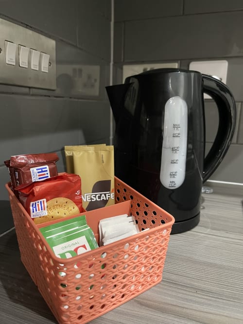 Hospitality welcome basket with coffee, tea, biscuits and Nescafé beside black kettle in Empire Serviced Apartments Leicester