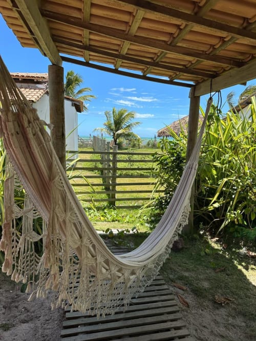 Redes em deck de madeira sob pérgola com vista para o oceano na Caraiva Cadu House, Brasil