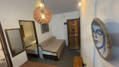 Quarto da Caraiva Cadu House com sofá listrado, luminária de vime, espelhos emoldurados e prato azul decorativo na parede