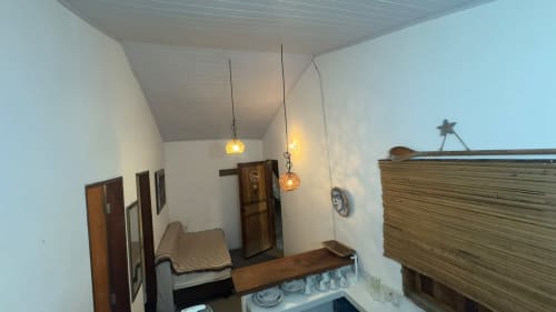Interiores do apartamento frente ao mar em Caraiva, com móveis de madeira, iluminação pendente e decoração costeira na Pousada Vênus