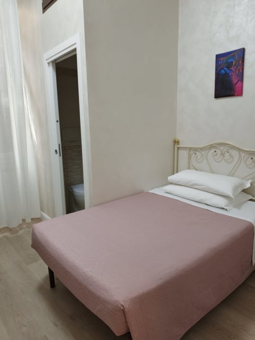 Compatta camera singola presso l'Hotel Principe Amedeo con biancheria rosa, testata in metallo bianco e bagno privato a Roma