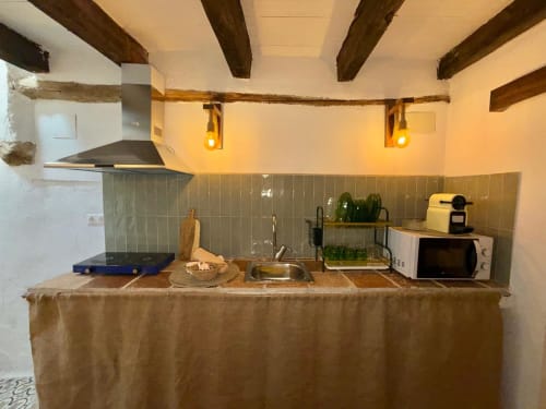 Cocina rústica en Casa de la Aguadora, Iznatoraf con vigas de madera, azulejos verdes y electrodomésticos modernos