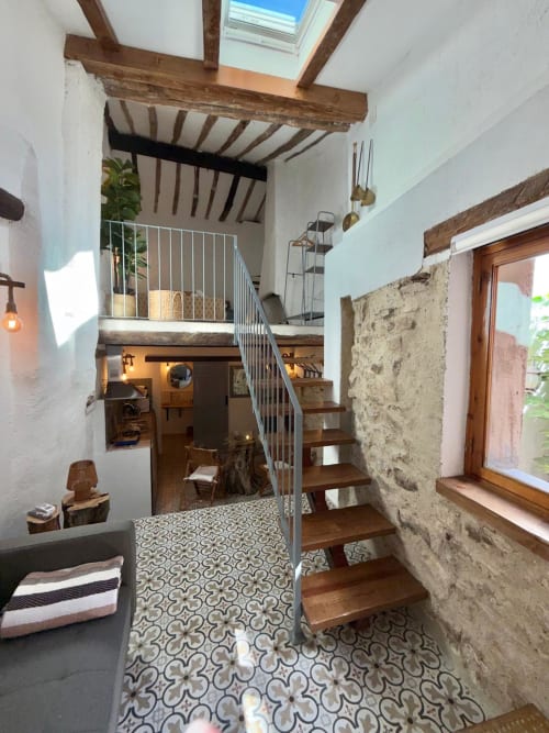 Escalera de la Sala Real de la Casa de la Aguadora con vigas vistas, baldosas de patrón y muros de piedra en Iznatoraf