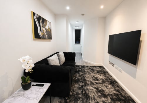 Modern one-bedroom suite at Empire Serviced Apartments Leicester with black sofa, wall-mounted TV, and contemporary décor