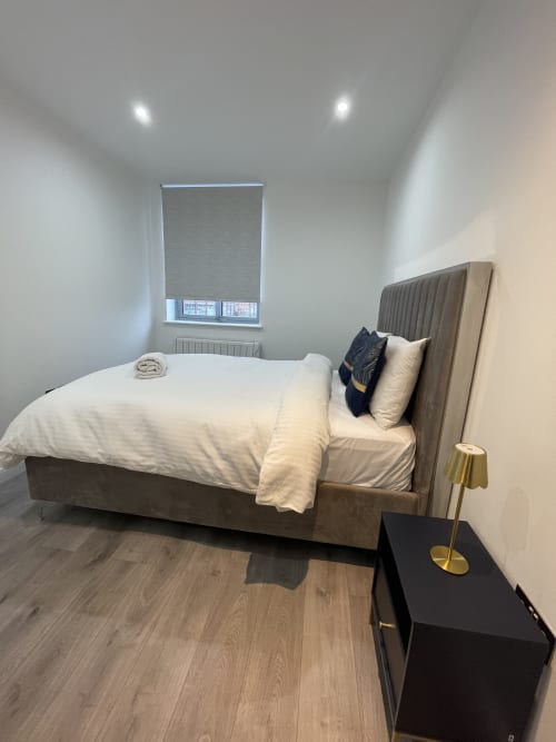 Modern bedroom at Empire Serviced Apartments in Leicester with queen bed, grey upholstered headboard, minimalist decor, and