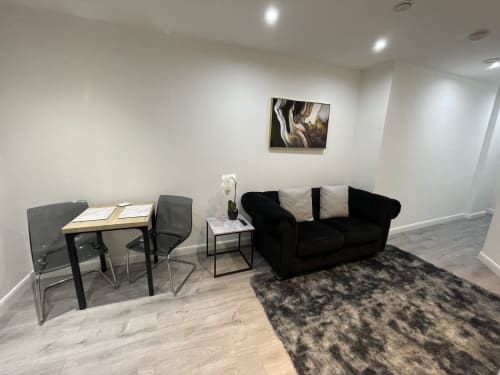 Modern one-bedroom suite at Empire Serviced Apartments Leicester with black sofa, desk, dining area, and city view