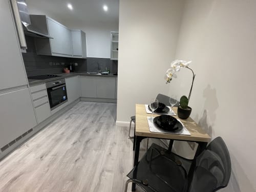 Modern one-bedroom suite at Empire Serviced Apartments Leicester with open-plan kitchen, dining area with white orchid plant,