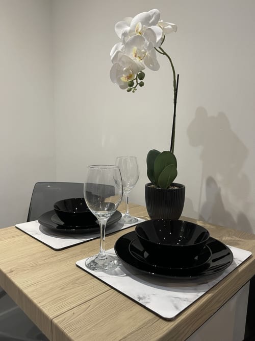 Elegant table setting at Empire Serviced Apartments Leicester with black dinnerware, wine glass, and white orchid centerpiece