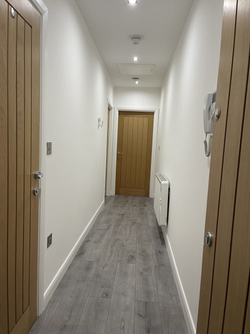 Modern hallway in Empire Serviced Apartments Leicester with grey wood flooring, white walls, and wooden doors leading to