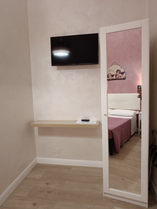 Camera matrimoniale Economy dell'Hotel Principe Amedeo con TV a parete, scrivania in legno e vista della camera con porte specchio rosa