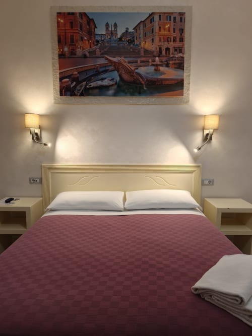 Standardzimmer im Hotel Principe Amedeo mit Doppelbett und burgunderroter Bettwäsche, Aussicht auf die Spanische Treppe von Rom vom Bett aus