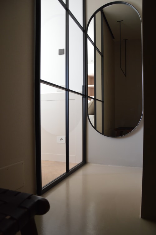 Ingresso moderno di una camera d'hotel con porta in vetro a cornice nera e specchio ovale a Villa Rosati a Sanzeno