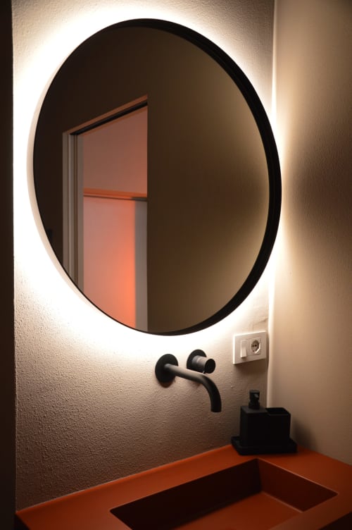 Specchio rotondo moderno con illuminazione LED sopra lavabo in terracotta nel bagno di Villa Rosati, Sanzeno