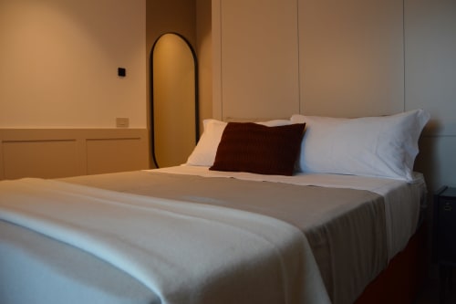 Camera da letto moderna a Villa Rosati con biancheria bianca, cuscino bordeaux e arredamento minimalista a Sanzeno