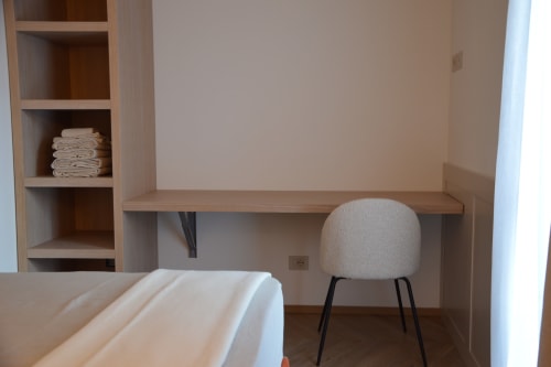 Camera Resina a Villa Rosati con scrivania, sedia, scaffali in legno e biancheria piegata a Sanzeno
