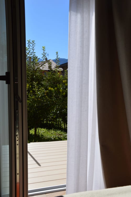 Porta aperta sulla terrazza privata di Villa Rosati a Sanzeno, vista giardino con piante fiorite e montagne