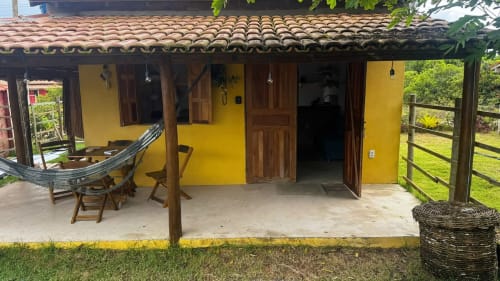 Cabana amarela com varanda de madeira, rede e terraço na Caraiva Cadu House em Porto Seguro