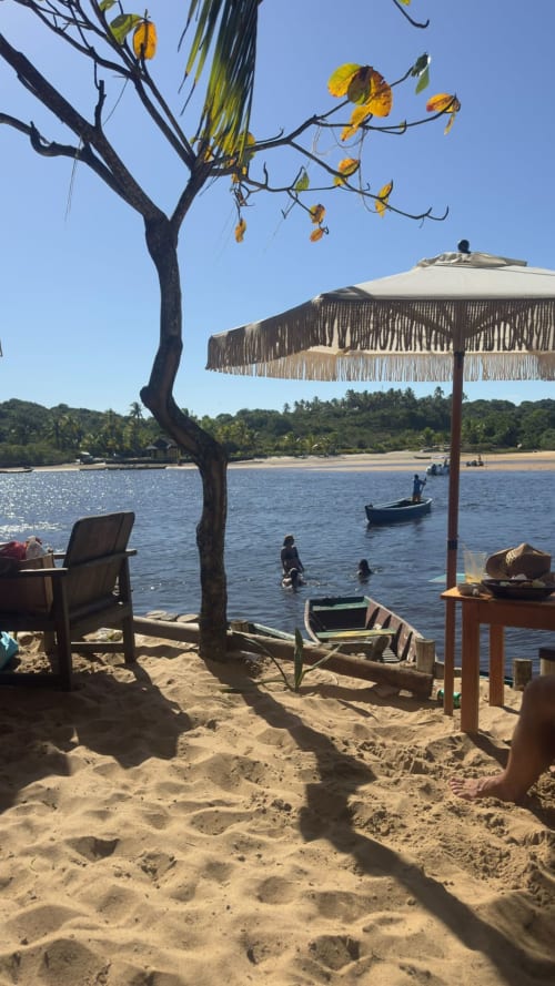 Relaxamento à beira-mar na Caraiva Cadu House, Porto Seguro, com praia de areia, barco de madeira, guarda-sol e acesso ao quarto de hóspedes