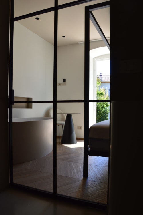 Moderna partizione in vetro nella sala Creta di Villa Rosati, che rivela un interno minimalista con vista sul giardino e pavimenti in legno