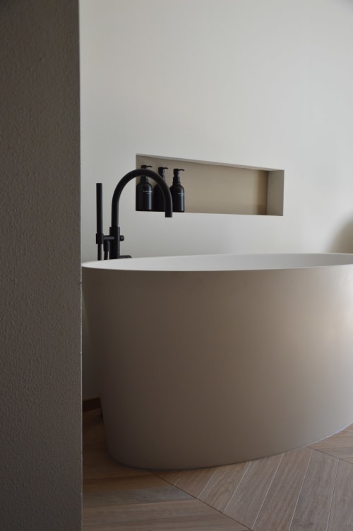 Vasca da bagno circolare bianca moderna con rubinetto nero e nicchia integrata con articoli da bagno a Villa Rosati a Sanzeno