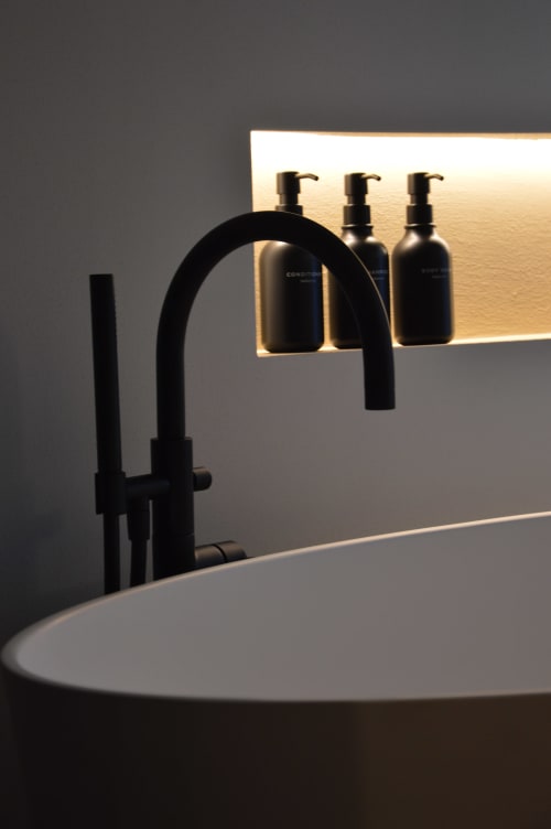 Lavabo moderno con rubinetto nero e bottigliette di cortesia presso l'hotel boutique Villa Rosati a Sanzeno