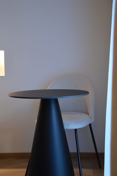 Zona living minimalista moderna a Villa Rosati con tavolo nero conico e poltrona rivestita in grigio nella sala Creta