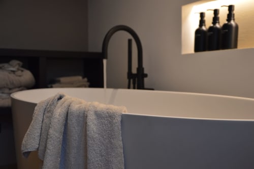 Lussuoso bagno di Villa Rosati con vasca freestanding, rubinetto nero e asciugamani grigi piegati a Sanzeno