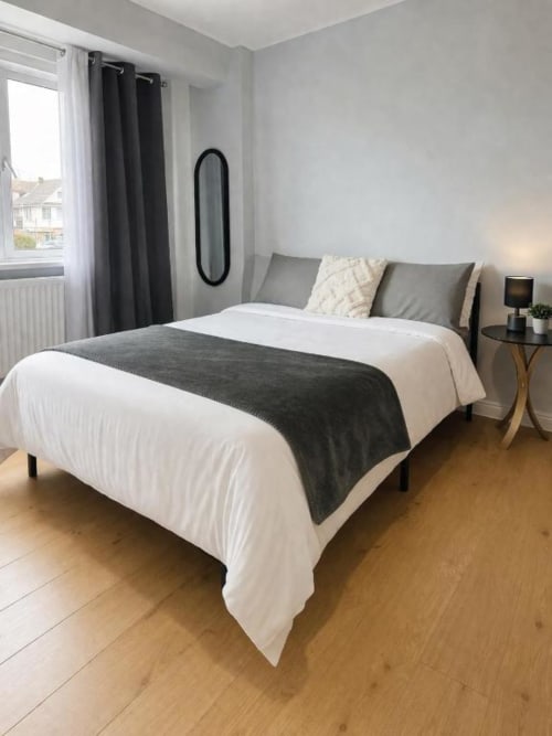Modern bedroom at Victoria House Cozy Rooms London with white and grey bedding, wooden floor, and garden view window