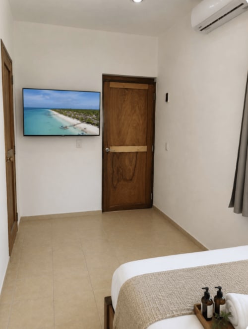 Suite del Hotel Holbox Centro con vista aérea de playa en TV, puertas de madera y comodidades modernas en Holbox, México