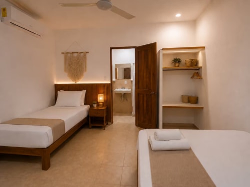 Suite Centro del Hotel Holbox con dos camas individuales, muebles de madera, baño abierto y repisas flotantes en Holbox, México