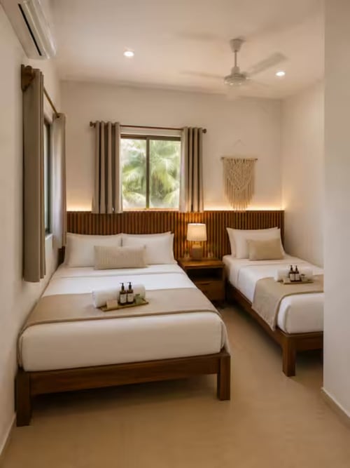 Habitación doble del Hotel Holbox Centro con camas de madera, sábanas blancas y vistas a los jardines tropicales de Holbox, México