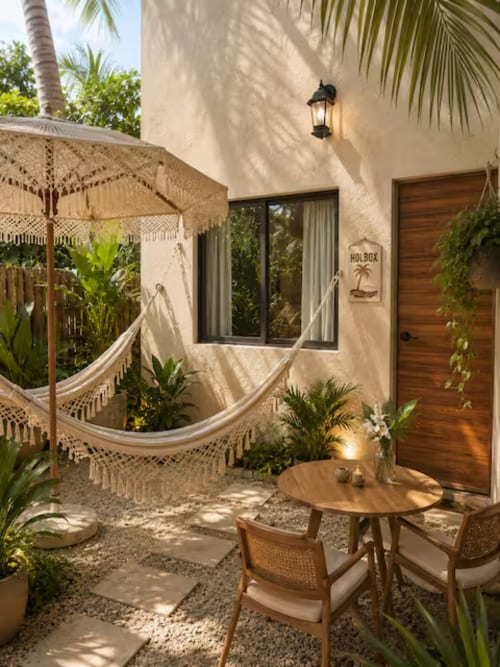 Suite del hotel Holbox con patio, hamaca, mesa de madera, sillas, plantas tropicales y arquitectura de casa de playa