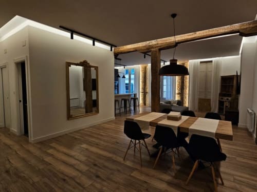 Comedor moderno del Hotel Izarbe en Burgos con mesa de madera, sillas negras y vigas rústicas en el techo