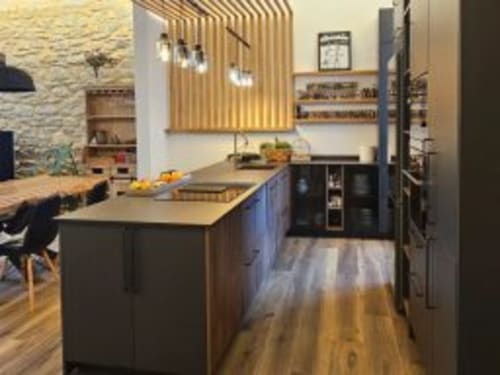 Cocina moderna del Hotel Izarbe en Burgos con isla central, luces colgantes y piso de madera