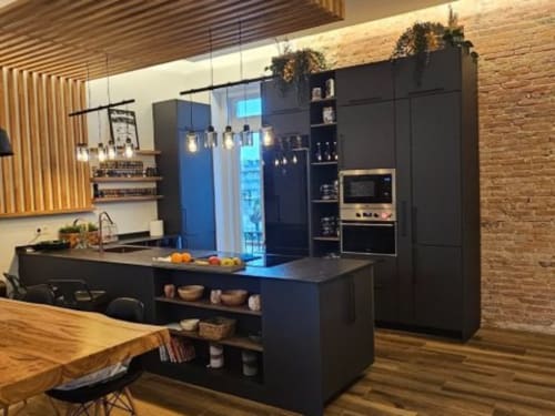 Cocina moderna negra con isla, refrigerador azul y detalles en madera en Hotel Izarbe Burgos
