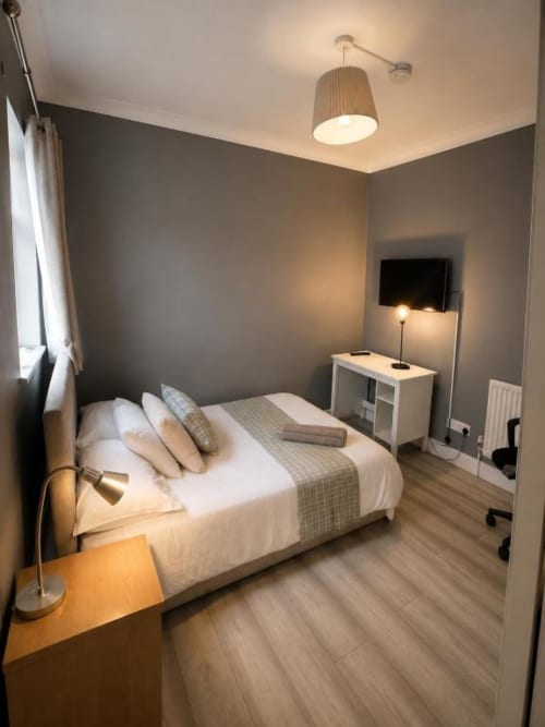 Cozy bedroom at Victoria House with double bed, grey walls, modern lighting, and TV at London B&B