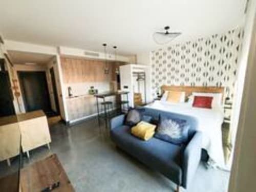 Estudio en Madrid Río con cama, sofá azul, cocina americana, papel tapiz estampado y comodidades modernas