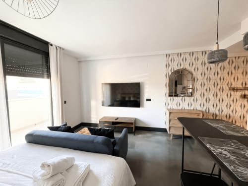 Estudio moderno en Madrid Río con sofá azul, TV de pared y mobiliario contemporáneo