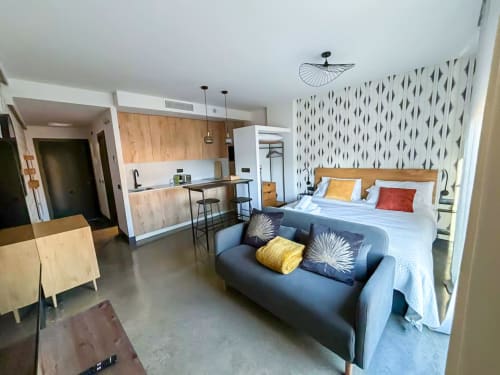 Moderno estudio en Madrid con cama, sofá, cocina americana y pared de acento con patrón