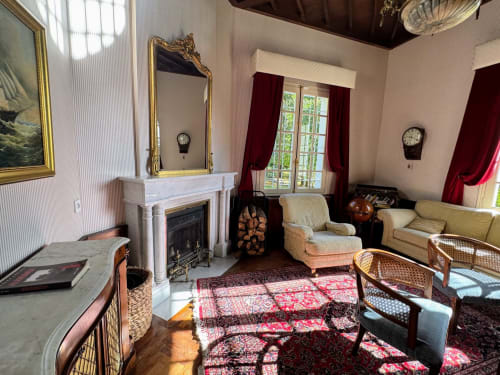 Elegantes Wohnzimmer des Domaine de Bize mit Kamin, verziertem Spiegel, Möbeln im Stil der Époque und Bergblick