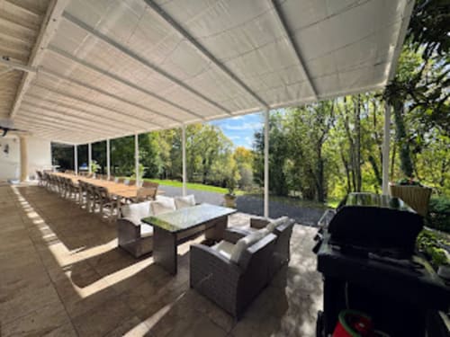 Schattierte Terrasse im Domaine de Bize in Mirepoix mit Lounge-Bereich, Esszimmer und Blick auf die umliegende Grünfläche