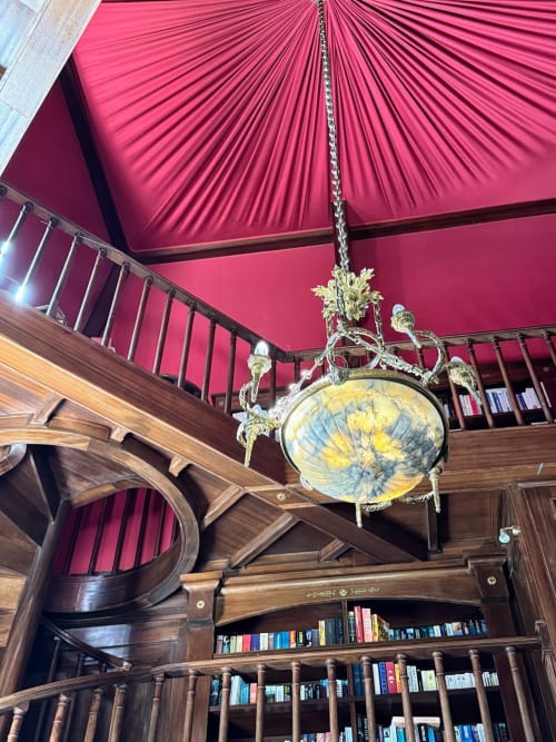 Prunkvoller Messingkronleuchter mit Globus, der von der rosa gefalteten Decke der holzvertäfelten Bibliothek im Domaine de Bize Mirepoix hängt