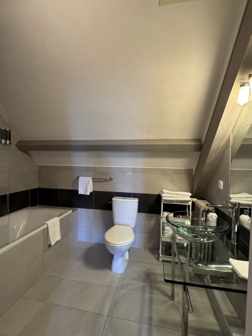 Modernes Badezimmer in der Mirepoix-Familiensuite mit Toilette, Badewanne, Waschbecken und schwarz-weißen Fliesenakzenten