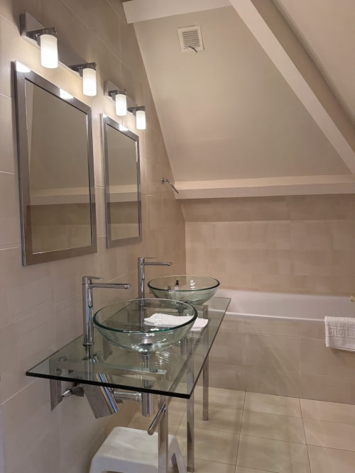 Modernes Badezimmer mit zwei gläsernen Aufsatzwaschbecken, Designer-Armaturen, gerahmten Spiegeln und Spiegelleuchten in der Familiensuite