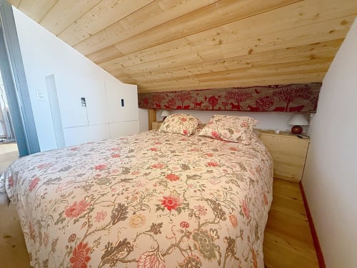 Chambre en mezzanine douillette avec literie florale et poutres apparentes au Flocon du Clocher, Montgenèvre